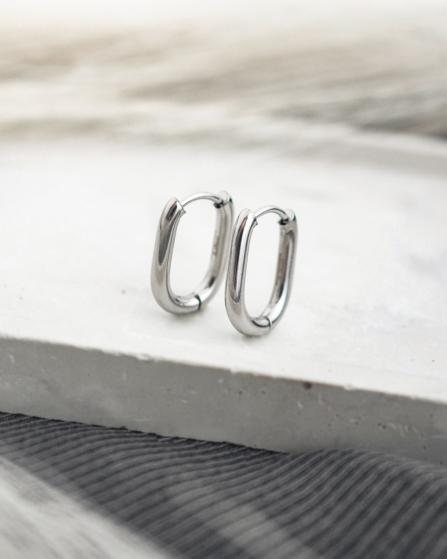 Silver hoop earrings on a light wooden surface
