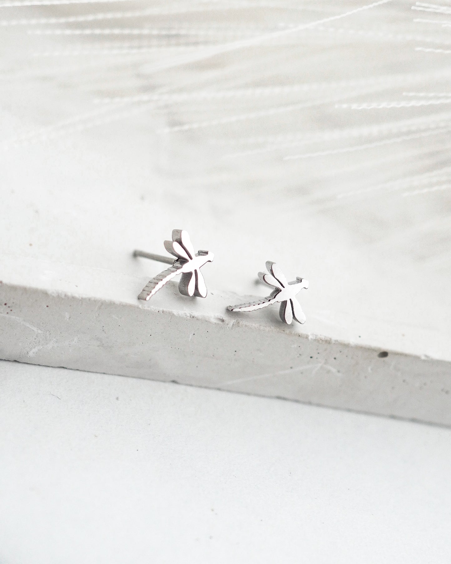 Silver earrings on a light wooden surface