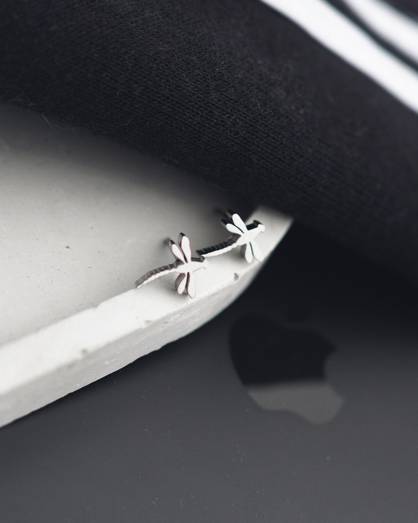 Silver earrings on a dark surface with a white background