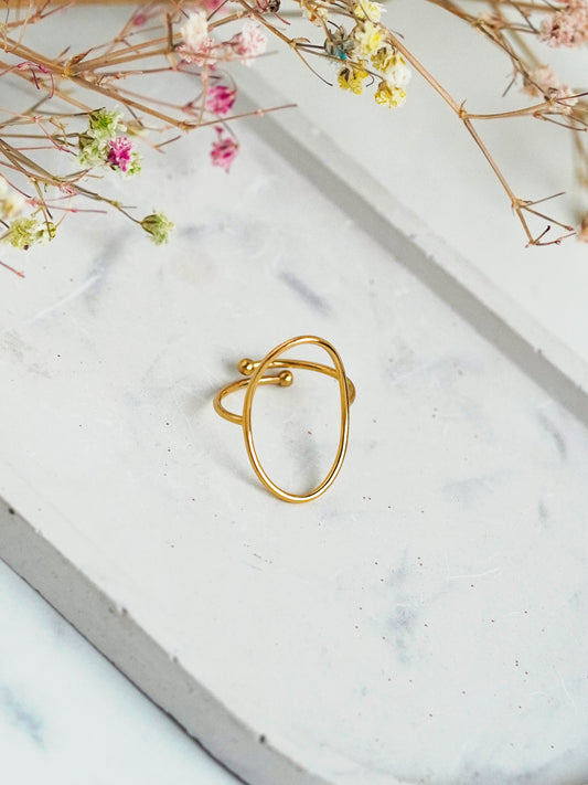 Gold-plated ring on a marble surface with dried flowers