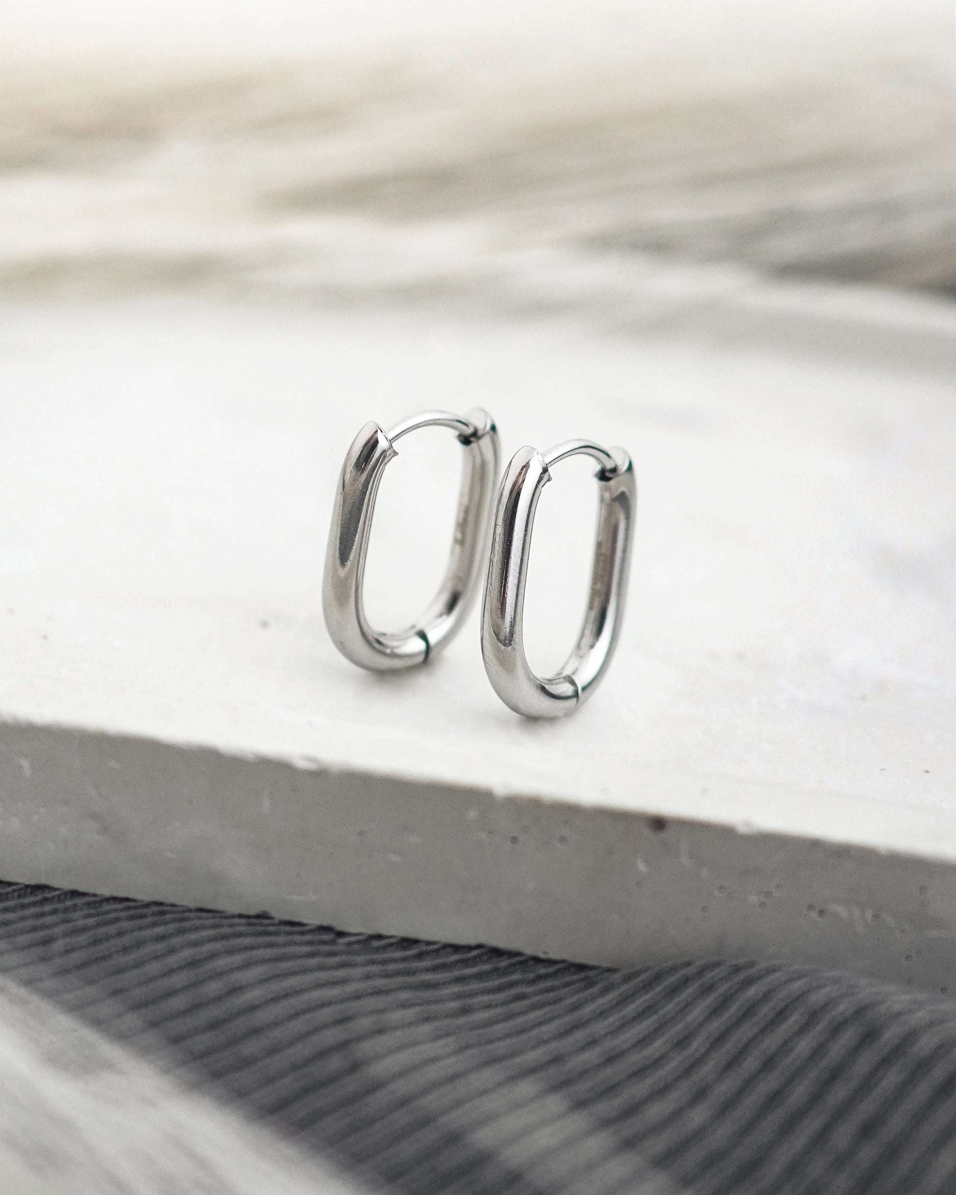 Silver hoop earrings on a light wooden surface