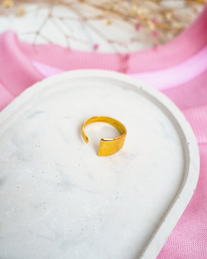 Gold ring on a white stone with a pink fabric background