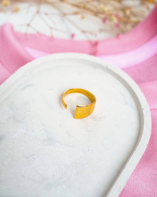 Gold ring on a white stone with a pink fabric background