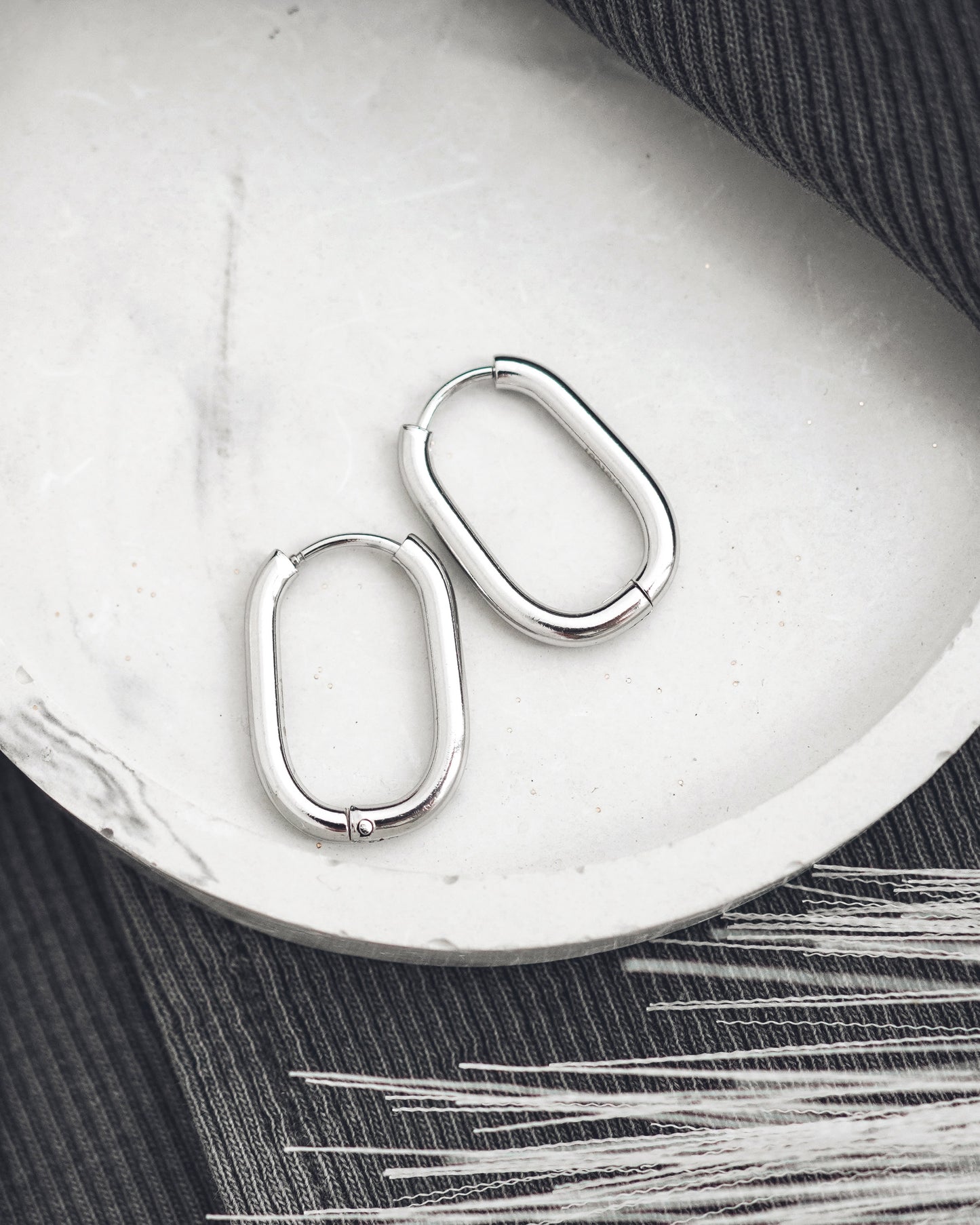 Pair of silver hoop earrings on a white surface