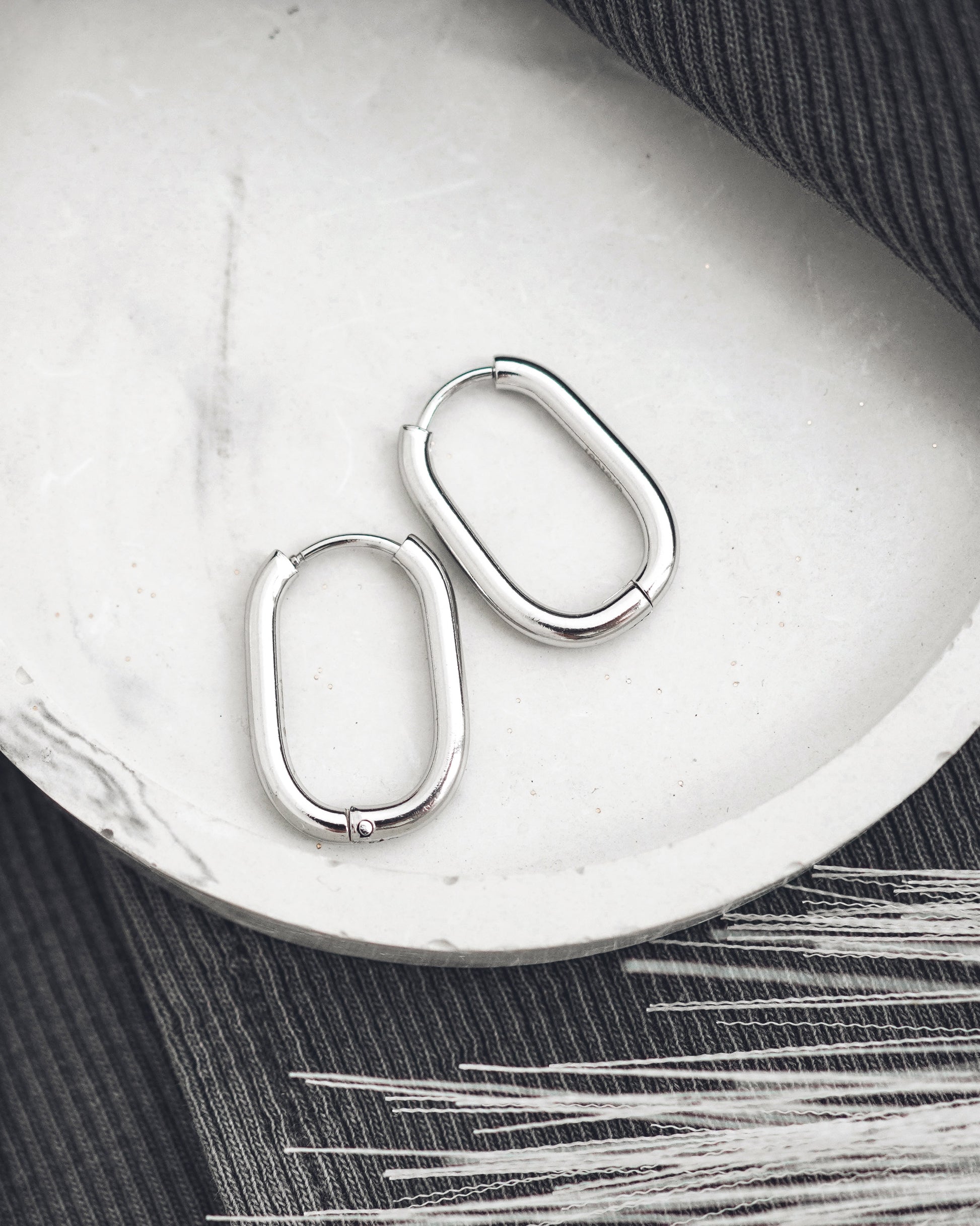 Pair of silver hoop earrings on a white surface