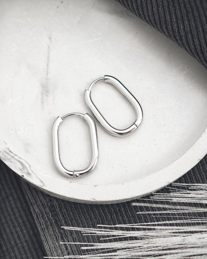 Pair of silver hoop earrings on a white surface