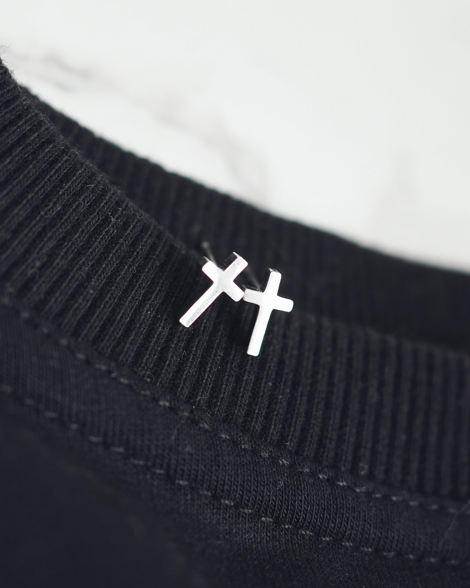 Black sweater with a white embroidered symbol on a white background