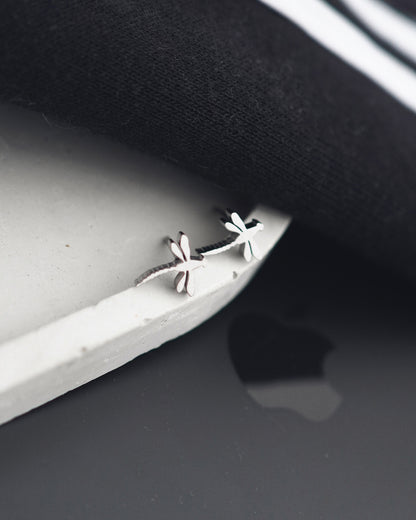 Silver earrings on a dark surface with a white background