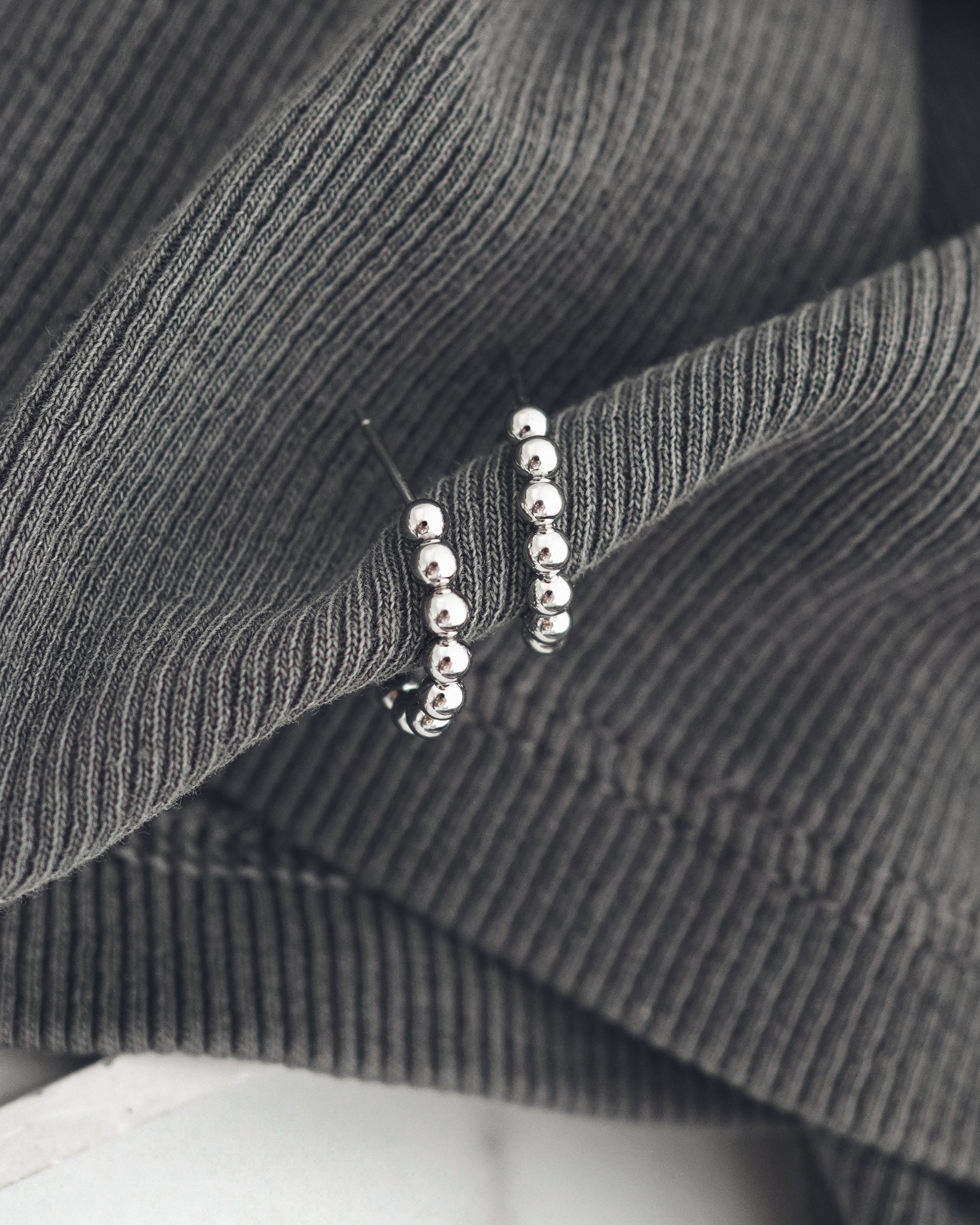 Close-up of a silver colored earrings on a textured gray fabric background