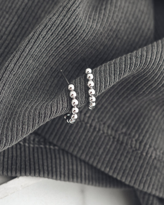 Close-up of a silver colored earrings on a textured gray fabric background
