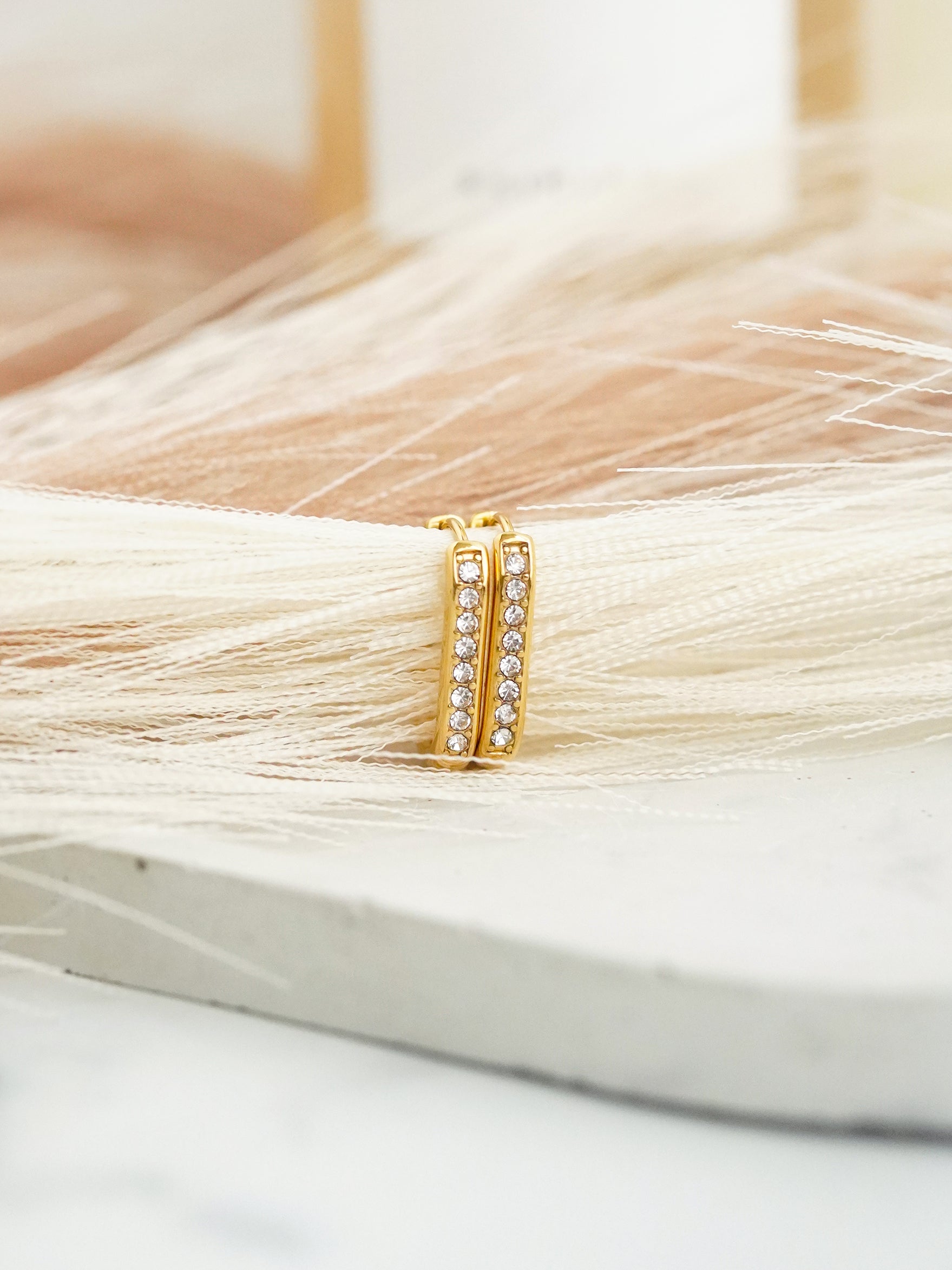 Gold hoop earrings with embedded stones on a white background