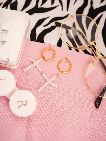 Gold hoop earrings and a necklace with pearls on a pink surface, with a zebra print background.