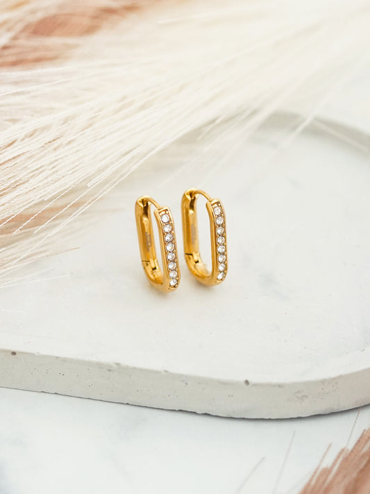 Gold-plated  hoop earrings with white crystals on a light background