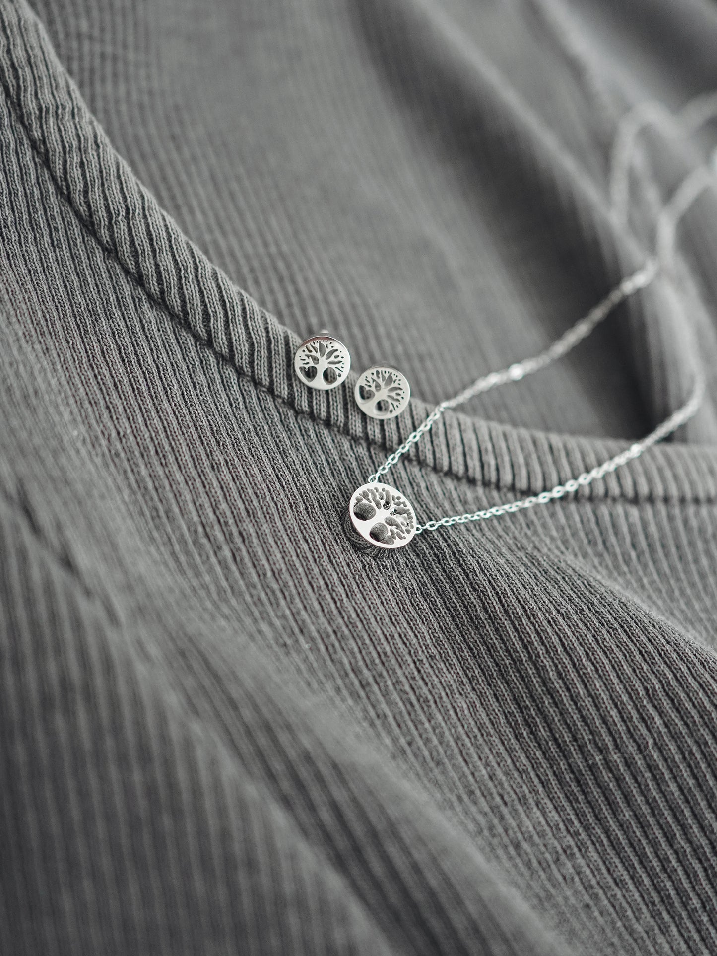 Silver necklace and earrings on a textured gray surface