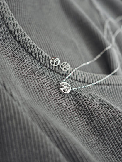 Silver necklace and earrings on a textured gray surface