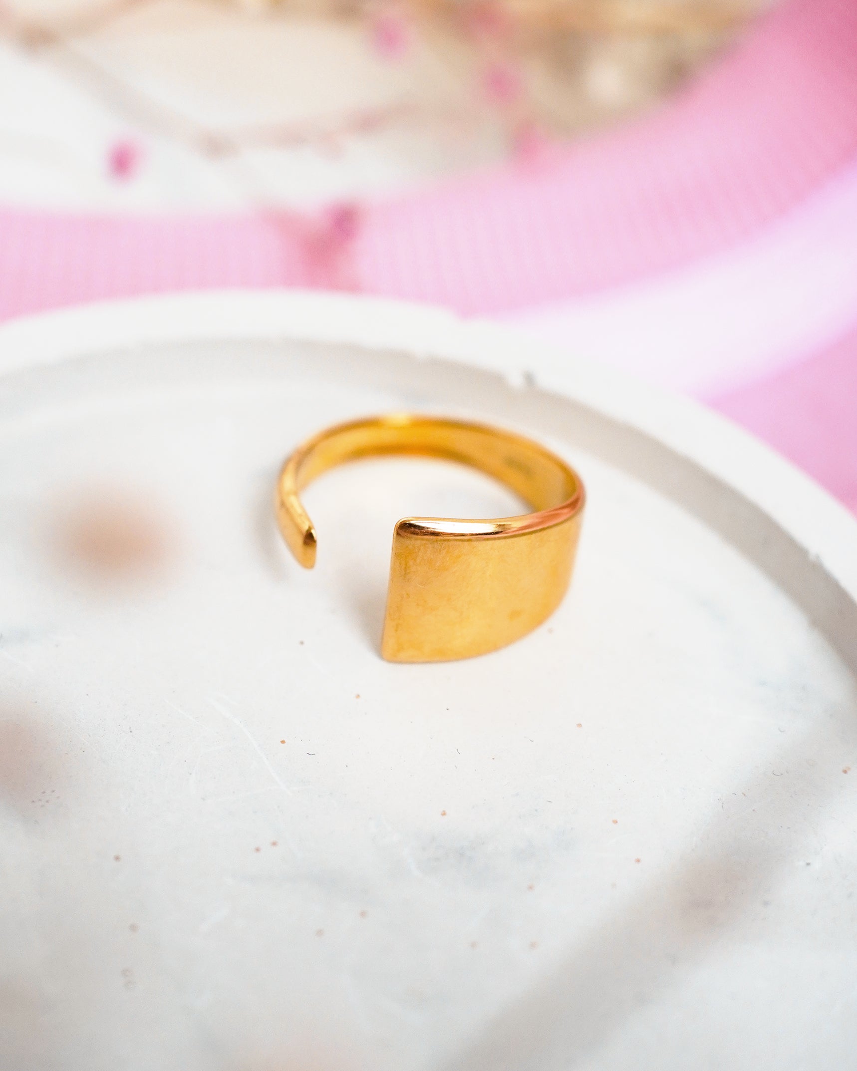 Gold ring on a white plate with a pink floral background
