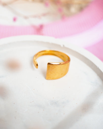 Gold ring on a white plate with a pink floral background