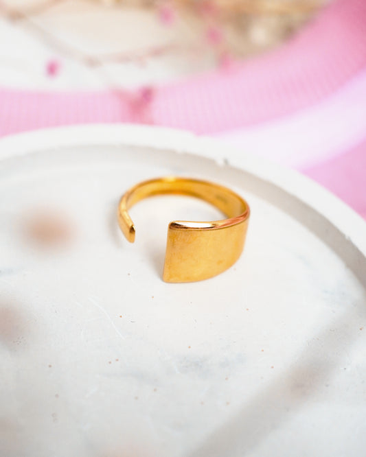 Gold ring on a white plate with a pink floral background