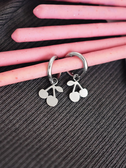 Silver hoop earrings with cherry designs on a hand against a black background