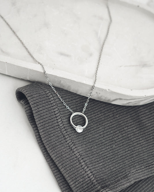 Silver necklace with a small pendant on a textured surface