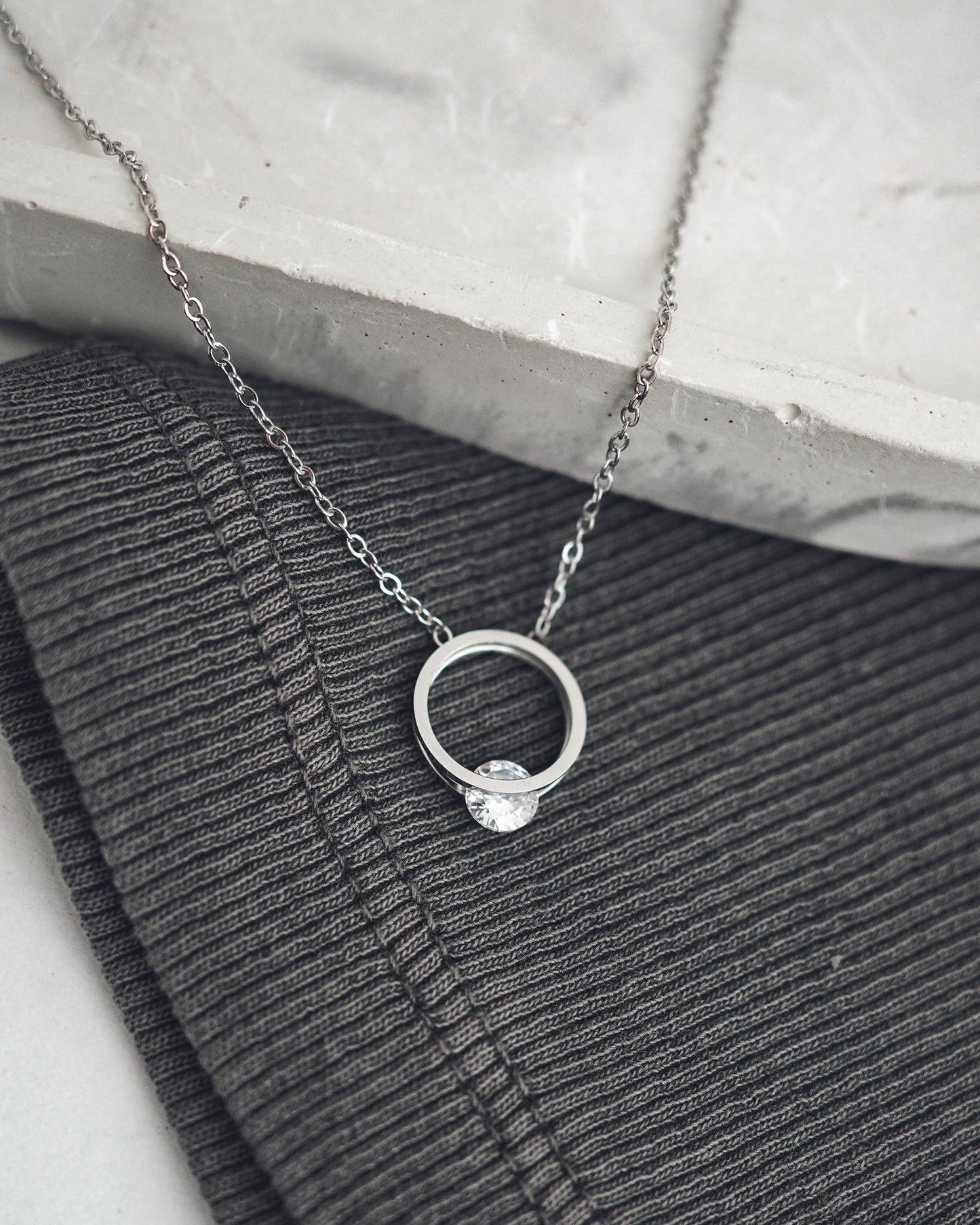 Silver necklace with a ring pendant on a textured surface