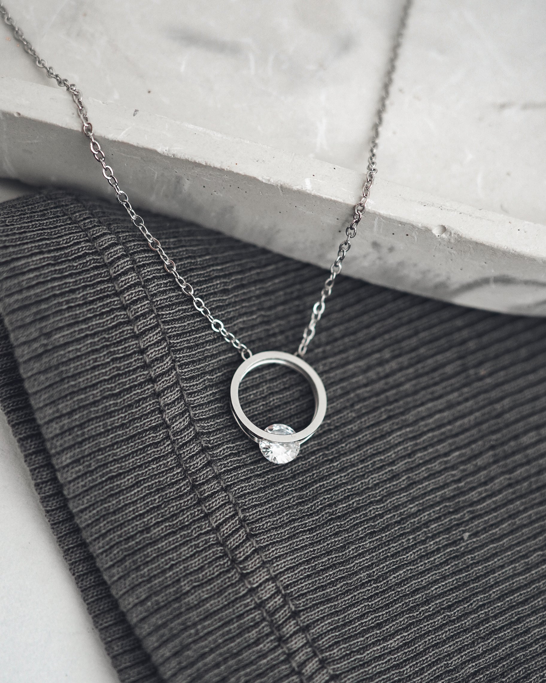 Silver necklace with a ring pendant on a textured surface