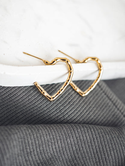Gold heart-shaped earrings on a textured surface