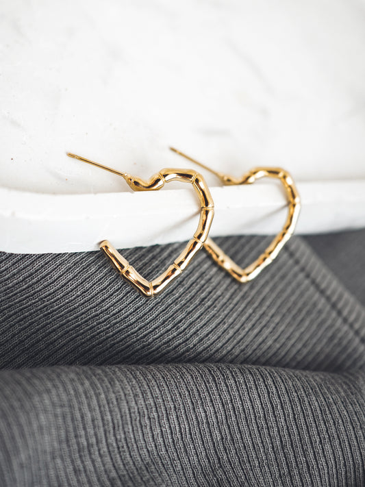 Gold heart-shaped earrings on a textured surface