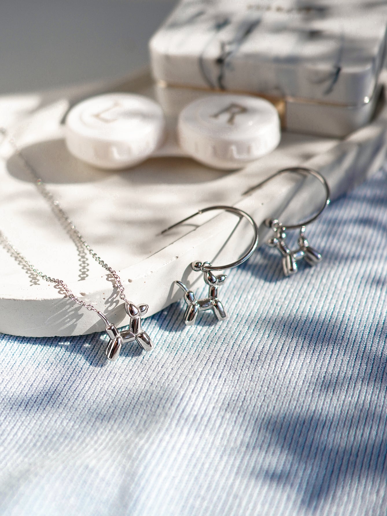 Silver jewelry set with necklace and earrings on a textured surface