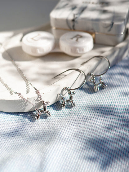 Silver jewelry set with necklace and earrings on a textured surface